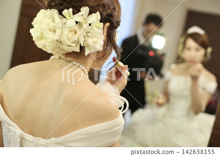 婚禮儀式前，準新娘在更衣室鏡子前完成唇妝，鏡頭從背後拍攝 | 婚禮場地和婚禮雜誌網站及廣告 142638155