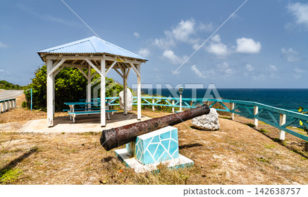 An old rusty cannon and wooden gazebo sit at a scenic coastal viewpoint overlooking the blue ocean in La Desirade, Guadeloupe. An old rusty cannon and wooden gazebo sit at a scenic coastal viewpoint overlooking the blue ocean in La Desirade, Guadeloupe. 142638757