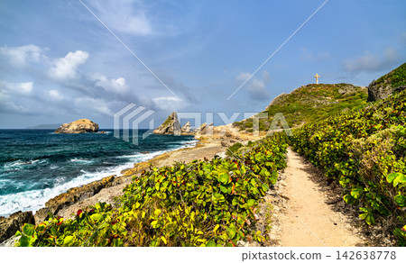 Hiking trail along the lush rocky coastline leading towards the famous cross at Pointe des Chateaux in Saint Francois, Guadeloupe, French West Indies. Hiking trail along the lush rocky coastline leading towards the famous cross at Pointe des Chateaux in Saint Francois, Guadeloupe, French West Indies. 142638778