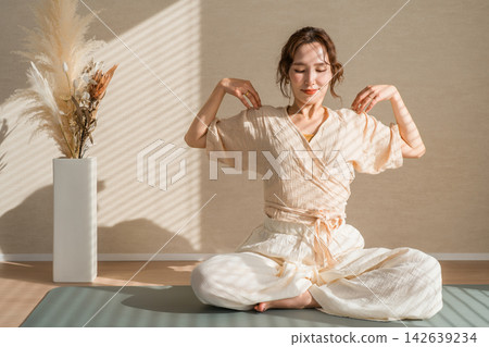 一位女士在晨光中練習瑜珈。這是一種舒緩身心的健康習慣,她穿著天然的瑜珈服。 一位女士在晨光中練習瑜珈。這是一種舒緩身心的健康習慣,她穿著天然的瑜珈服。 142639234