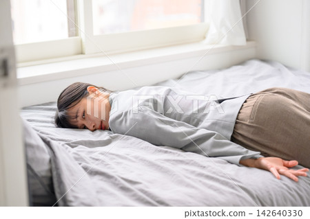 A businesswoman lies exhausted in bed. 142640330