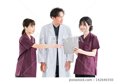 一名醫生和幾名女醫務人員一邊看著平板電腦一邊交流訊息。三人面帶微笑,協同工作。 一名醫生和幾名女醫務人員一邊看著平板電腦一邊交流訊息。三人面帶微笑,協同工作。 142640350