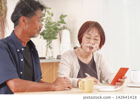 一對夫婦一邊查看退休金帳簿,一邊討論他們的退休計畫。 一對夫婦一邊查看退休金帳簿,一邊討論他們的退休計畫。 142641418