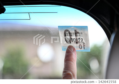 一位老人的手正在幫車輛貼年檢貼紙。 一位老人的手正在幫車輛貼年檢貼紙。 142641558