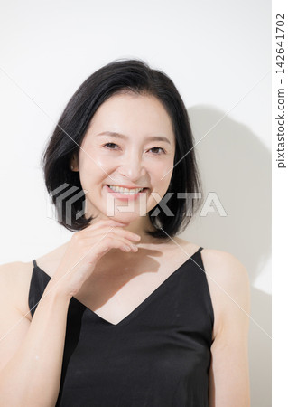 一位50歲的女性，擁有美麗、容光煥發的肌膚和自然的表情，對著鏡頭露出燦爛的笑容；護膚和抗衰老護理。 142641702