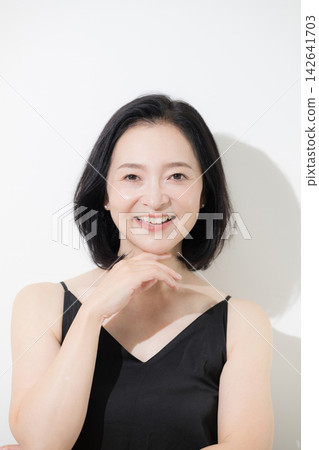 A 50-year-old woman with beautiful, glowing skin and a natural expression smiles directly at the beauty camera; skincare and anti-aging care. A 50-year-old woman with beautiful, glowing skin and a natural expression smiles directly at the beauty camera; skincare and anti-aging care. 142641703