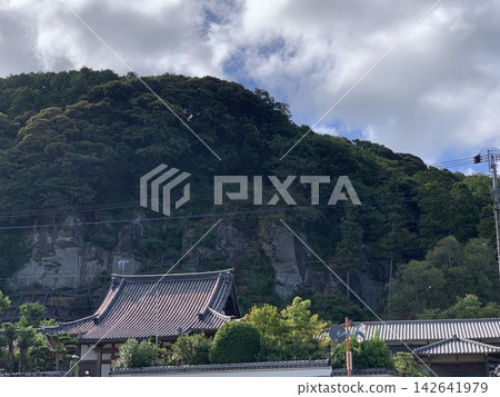 日式寺廟和瓦片屋頂,映襯著鬱鬱蔥蔥的青山和嶙峋的峭壁。 日式寺廟和瓦片屋頂,映襯著鬱鬱蔥蔥的青山和嶙峋的峭壁。 142641979