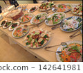 A buffet table laden with colorful dishes. 142641981