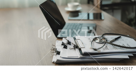 Stethoscope on financial reports beside Stethoscope on financial reports beside 142642017