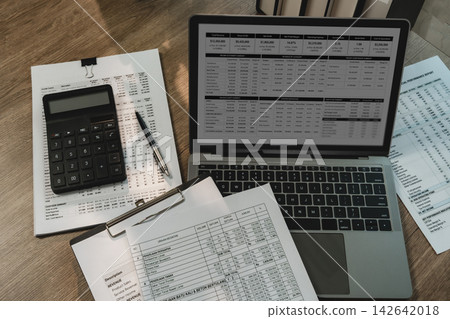 Laptop dashboard, calculator, financial reports, clipboard on desk for invoice review, receipt Laptop dashboard, calculator, financial reports, clipboard on desk for invoice review, receipt 142642018