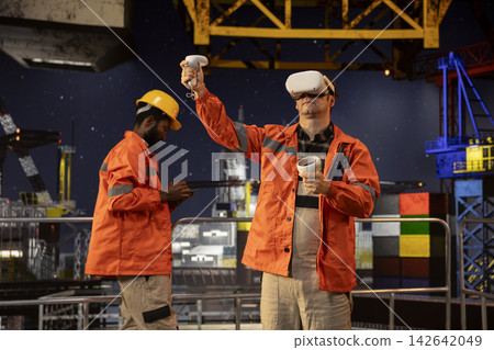 Industrial oil rig worker uses VR glasses to practice safety protocols, training with immersive simulations to enhance performance and ensure secure petroleum production at sea. Industrial oil rig worker uses VR glasses to practice safety protocols, training with immersive simulations to enhance performance and ensure secure petroleum production at sea. 142642049