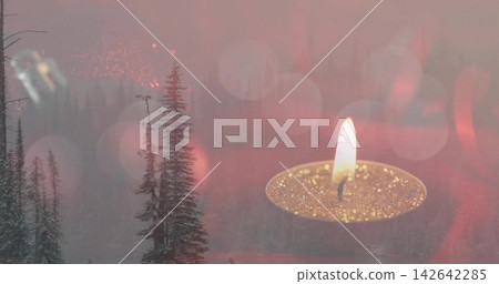 Glowing tealight candle in glitter gold cup flickering over misty evergreen trees, circular bokeh Glowing tealight candle in glitter gold cup flickering over misty evergreen trees, circular bokeh 142642285