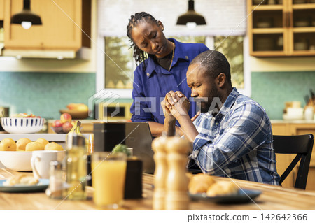 Sad black boyfriend appears disappointed after receiving bad news on his computer while the girlfriend comforts him with care. Couple going through stress, failure and disappointment. Sad black boyfriend appears disappointed after receiving bad news on his computer while the girlfriend comforts him with care. Couple going through stress, failure and disappointment. 142642366