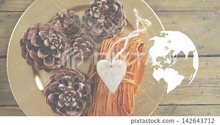 Displaying flat-lay with four pine cones, bound straw and white heart on gold plate, map overlay Displaying flat-lay with four pine cones, bound straw and white heart on gold plate, map overlay 142643712