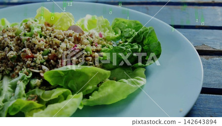 Displaying blue plate holding butter lettuce grain salad on blue patio table, faint green numbers Displaying blue plate holding butter lettuce grain salad on blue patio table, faint green numbers 142643894