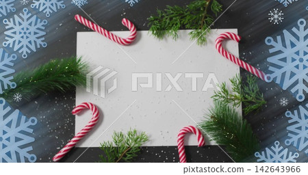 Displaying blank white card on dark wooden tabletop, with candy canes, pine sprigs, blue snowflakes 142643966