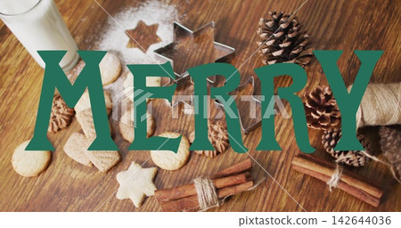 Floating green MERRY graphic overlay spanning wooden tabletop, covering cookies, star cutter, milk Floating green MERRY graphic overlay spanning wooden tabletop, covering cookies, star cutter, milk 142644036