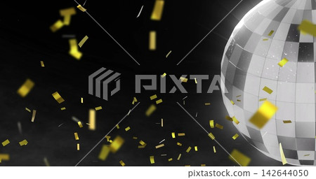 Rotating silver mirrored disco ball reflecting light in dark studio, with gold confetti, copy space 142644050