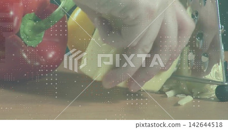 Grating adult hand holding pale food block on wooden counter with stainless grater, red bell pepper Grating adult hand holding pale food block on wooden counter with stainless grater, red bell pepper 142644518