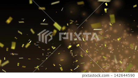 Falling gold confetti drifting across dark warm backdrop in studio, with glowing particles Falling gold confetti drifting across dark warm backdrop in studio, with glowing particles 142644590