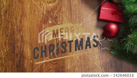 Displaying MERRY CHRISTMAS text on wood tabletop, showing red box and bauble, gold star, pine sprig Displaying MERRY CHRISTMAS text on wood tabletop, showing red box and bauble, gold star, pine sprig 142646018