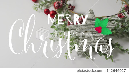 Resting rustic star on wreath with red berries on gray tabletop, white Merry Christmas script Resting rustic star on wreath with red berries on gray tabletop, white Merry Christmas script 142646027