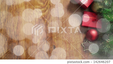 Displaying holiday decor on wooden table with bokeh overlays red gifts baubles star fir, copy space Displaying holiday decor on wooden table with bokeh overlays red gifts baubles star fir, copy space 142646207