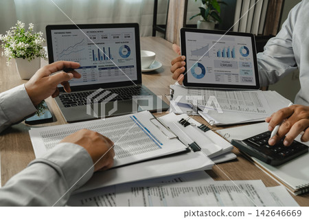Two businessmen analyzing financial dashboards during business meeting with spreadsheet reports and calculator on laptop and tablet for data analysis and performance review. 142646669