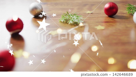 Styling tabletop with red baubles, fairy lights, fir sprigs, gold stars on wooden surface Styling tabletop with red baubles, fairy lights, fir sprigs, gold stars on wooden surface 142646689