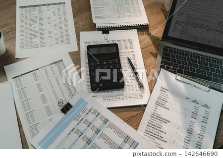 Tax form preparation workspace with laptop, calculator and financial reports for accounting, tax filing, audit, bookkeeping and financial planning. Tax form preparation workspace with laptop, calculator and financial reports for accounting, tax filing, audit, bookkeeping and financial planning. 142646690