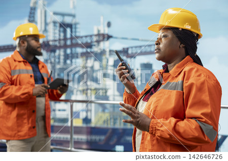 Offshore platform technician using two way radio communication to coordinate with coworkers. Drilling rig engineer speaks in walkie talkie, working together with technical team Offshore platform technician using two way radio communication to coordinate with coworkers. Drilling rig engineer speaks in walkie talkie, working together with technical team 142646726
