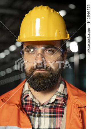 Engineering professional in helmet reviewing metalwork in industry hall. Massive beams, mechanical systems and advanced technology emphasize heavy industry manufacturing process. Engineering professional in helmet reviewing metalwork in industry hall. Massive beams, mechanical systems and advanced technology emphasize heavy industry manufacturing process. 142646773