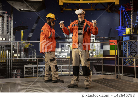 Male engineer using virtual reality equipment to inspect offshore drilling rig, applying advanced visualization for oil platform operations, maintenance and manufacturing systems. Male engineer using virtual reality equipment to inspect offshore drilling rig, applying advanced visualization for oil platform operations, maintenance and manufacturing systems. 142646798