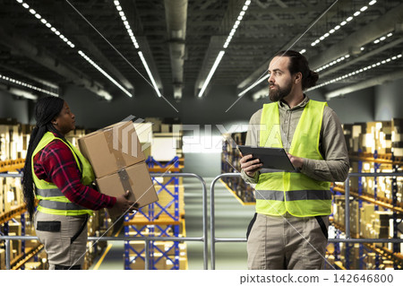 Male worker checking order logistics on tablet in warehouse space, managing shipment and distribution details. Man ensuring cargo packages for e-commerce inventory control, large business. Male worker checking order logistics on tablet in warehouse space, managing shipment and distribution details. Man ensuring cargo packages for e-commerce inventory control, large business. 142646800