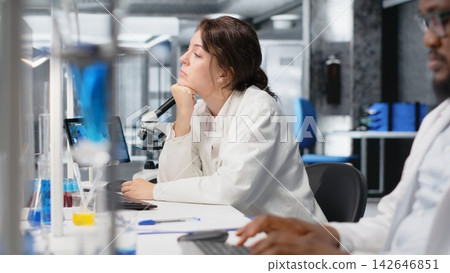 Laboratory manager oversees scientists working on computer, processing DNA data. Lab team leader and employees looking at genetic analysis diagnostics, brainstorming scientific breakthroughs, camera B Laboratory manager oversees scientists working on computer, processing DNA data. Lab team leader and employees looking at genetic analysis diagnostics, brainstorming scientific breakthroughs, camera B 142646851
