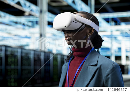 Software developer in data center using VR headset to monitor rigs. Computer scientist in server room using virtual reality technology to enhance operational effectiveness of infrastructure, closeup Software developer in data center using VR headset to monitor rigs. Computer scientist in server room using virtual reality technology to enhance operational effectiveness of infrastructure, closeup 142646857