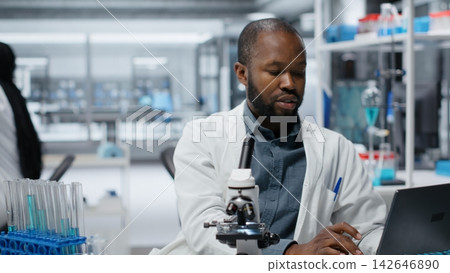 Molecular biologist in lab investigating blue liquid polymer properties in test tube container. Medical professional testing new synthetic material durability and viscosity in lab Molecular biologist in lab investigating blue liquid polymer properties in test tube container. Medical professional testing new synthetic material durability and viscosity in lab 142646890
