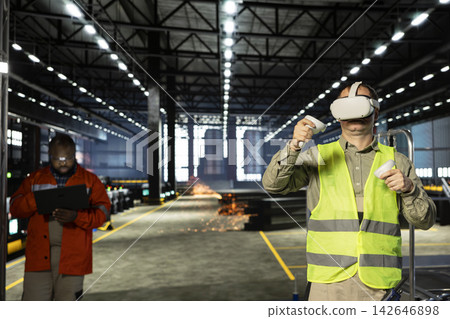Industrial personnel uses VR glasses to test 3D simulation for heavy machinery in hi vis vest, managing modern manufacturing process on factory floor. Professional workflow in warehouse. Industrial personnel uses VR glasses to test 3D simulation for heavy machinery in hi vis vest, managing modern manufacturing process on factory floor. Professional workflow in warehouse. 142646898