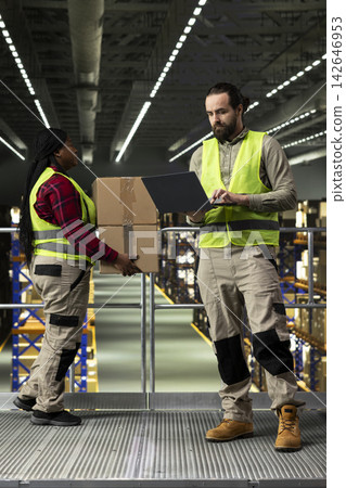 Male operator, shipment planning, safety vest, facility platform, workers representing operational efficiency and inventory control. Organized e-commerce parcel transportation in industry. Male operator, shipment planning, safety vest, facility platform, workers representing operational efficiency and inventory control. Organized e-commerce parcel transportation in industry. 142646953