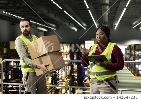 African american female staff using headset to handle package tracking, cargo status and customer complaints on a call. Woman transmitting parcel tracking info for e-commerce services. African american female staff using headset to handle package tracking, cargo status and customer complaints on a call. Woman transmitting parcel tracking info for e-commerce services. 142647233