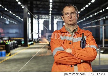 Portrait of operator standing in industrial workshop facility with safety glasses, ensuring steel fabrication and production with tools and machinery. Warehouse environment demands. Portrait of operator standing in industrial workshop facility with safety glasses, ensuring steel fabrication and production with tools and machinery. Warehouse environment demands. 142647351