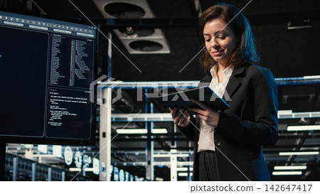 Data center programmer coding on tablet, scanning equipment rigs to create digital twin. Female technician in server hub running programming script on device, VFX compositing Data center programmer coding on tablet, scanning equipment rigs to create digital twin. Female technician in server hub running programming script on device, VFX compositing 142647417