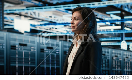 Smiling data center manager taking virtual tour using AR technology, pleased by performance. Happy woman walking in server hub with blue wireframe mesh gear augmented reality simulation Smiling data center manager taking virtual tour using AR technology, pleased by performance. Happy woman walking in server hub with blue wireframe mesh gear augmented reality simulation 142647423
