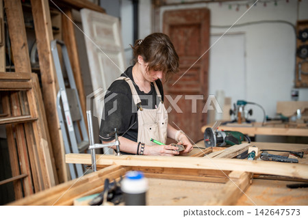 Focused woman restorer works in restoration workshop at workbench with vintage frame and instruments Focused woman restorer works in restoration workshop at workbench with vintage frame and instruments 142647573