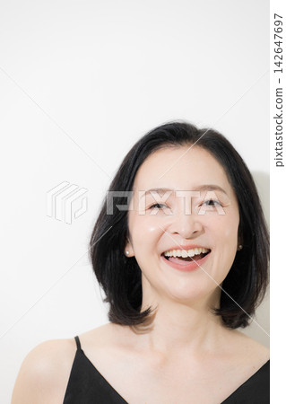 A 50-year-old woman with beautiful skin laughs heartily in a beauty portrait, looking directly at the camera with a smile; skincare and anti-aging care. A 50-year-old woman with beautiful skin laughs heartily in a beauty portrait, looking directly at the camera with a smile; skincare and anti-aging care. 142647697