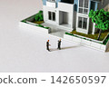 A business person considering purchasing a home and a model of a detached house. 142650597