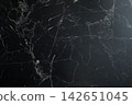 Marble backdrop exhibits dark tones with striking white veins 142651045