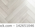 Light wooden flooring showcases elegant herringbone pattern 142651046