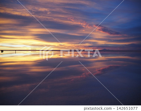 Bolivia's Uyuni Salt Flats: Dramatic sunset clouds and a vast, gradient sky reflected in the water's mirror-like surface. 142651077