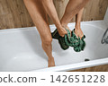Person drying feet with towel after shower in bathroom 142651228